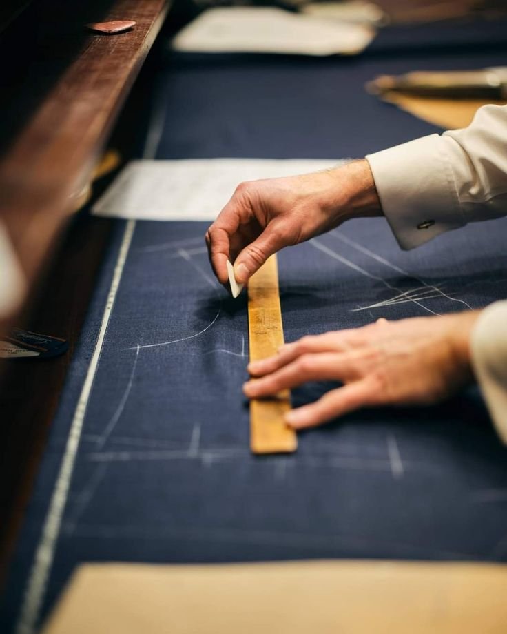 Tailor chalking a suit pattern on navy fabric